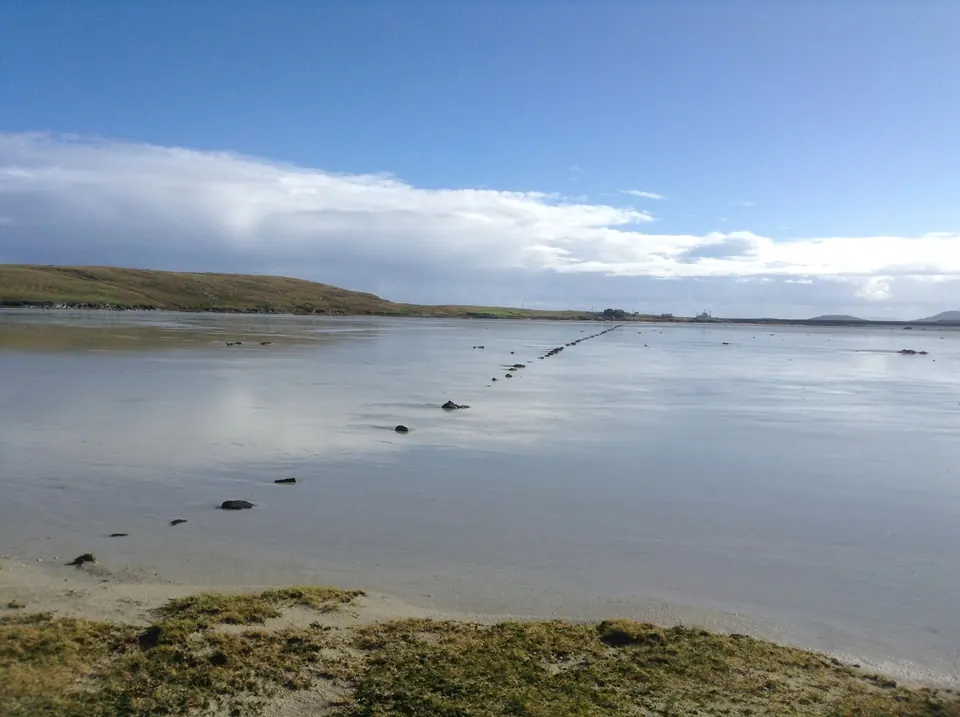 The Cockle Beach at low tide beside the bunkhouse, looking across the water to North Uist under a wide sky